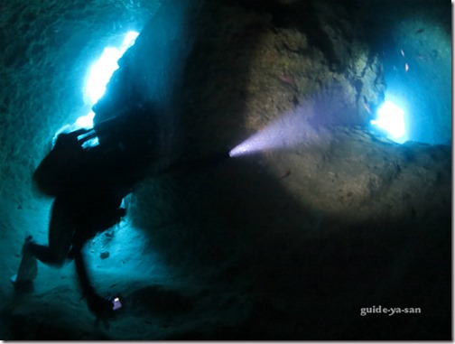 水中洞窟でライトを持ってダイビングを楽しむダイバー