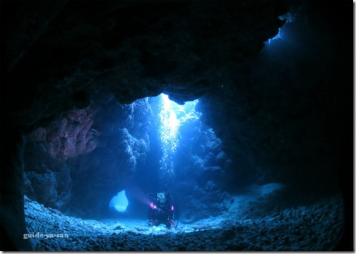 水中洞窟に差し込む光を見上げるダイバー